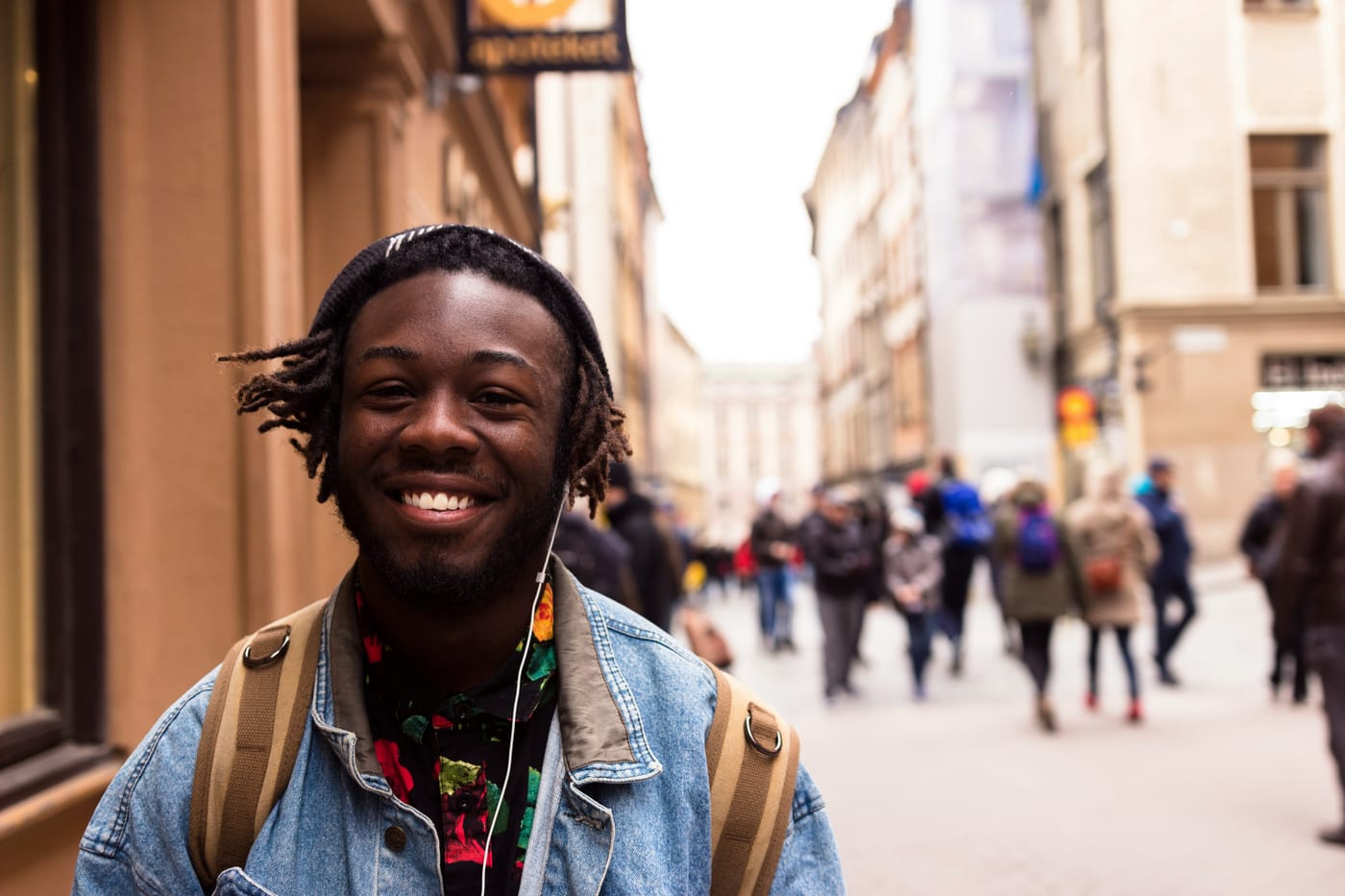 A smiling student with a backpack on a busy city street.